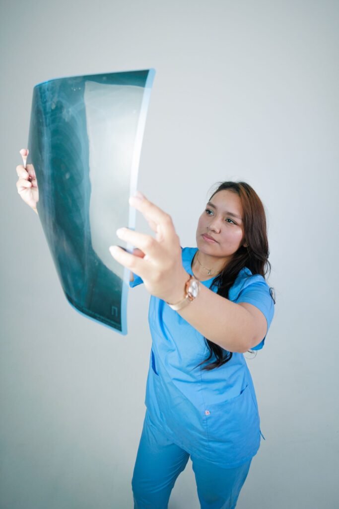 Doctor in scrubs examining an X-ray film, representing care during an inpatient stay where a family attendant stays nearby