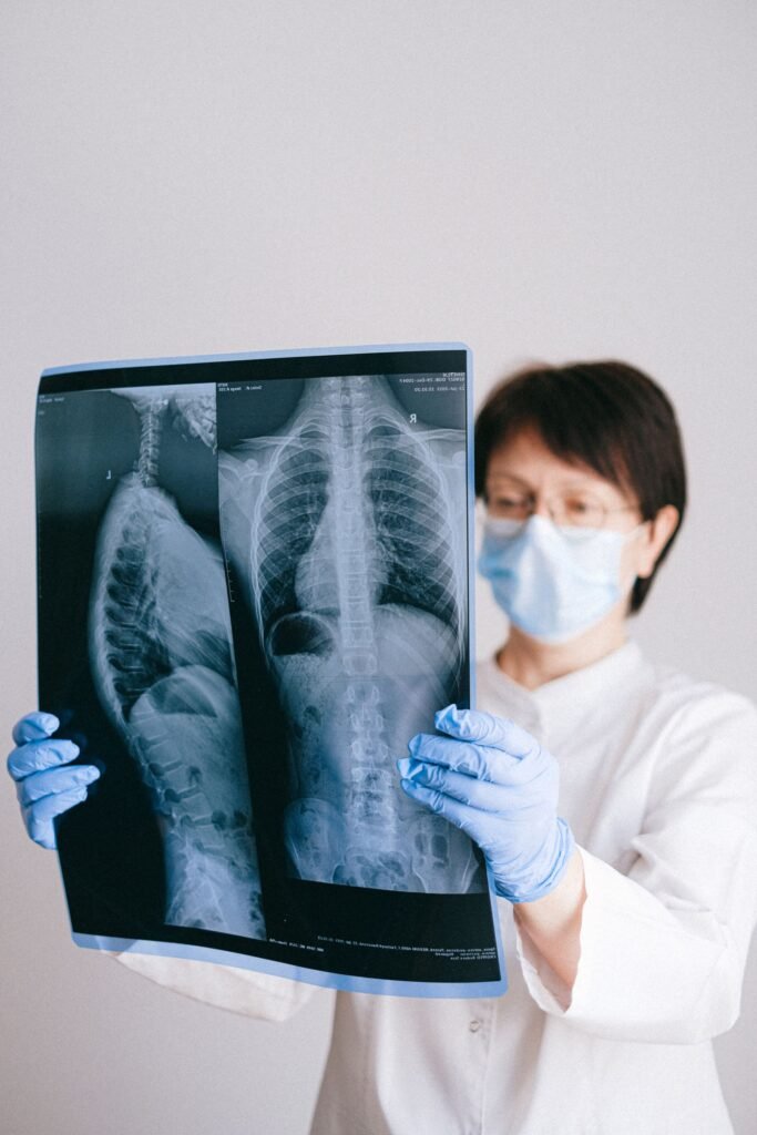 Doctor wearing a mask and gloves examining an X-ray, representing review appointments and follow-up after treatment in Delhi
