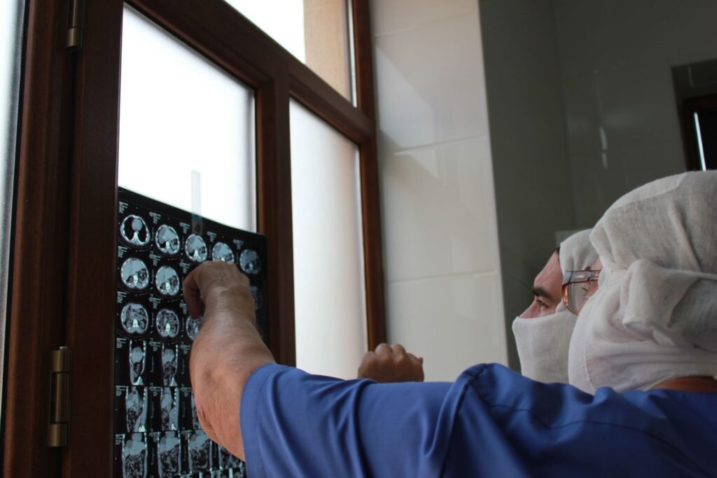Doctor examining an X-ray film by a window in a clinic, representing review appointments and follow-up after treatment in Kochi