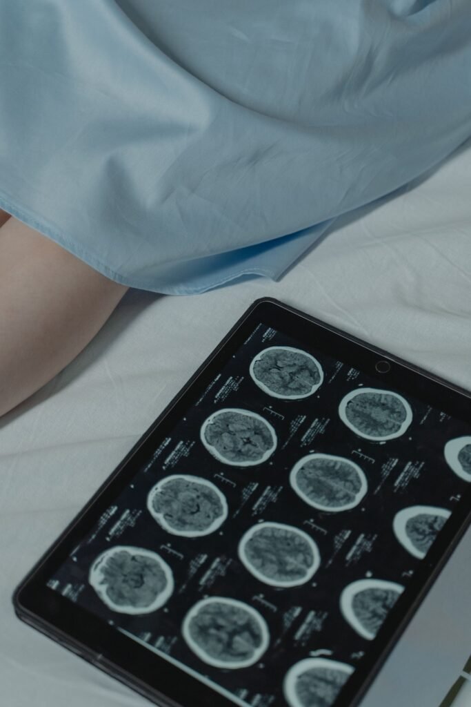 Brain scan results shown on a digital tablet beside a patient in hospital, representing the tests and repeat reviews common during treatment in Vellore