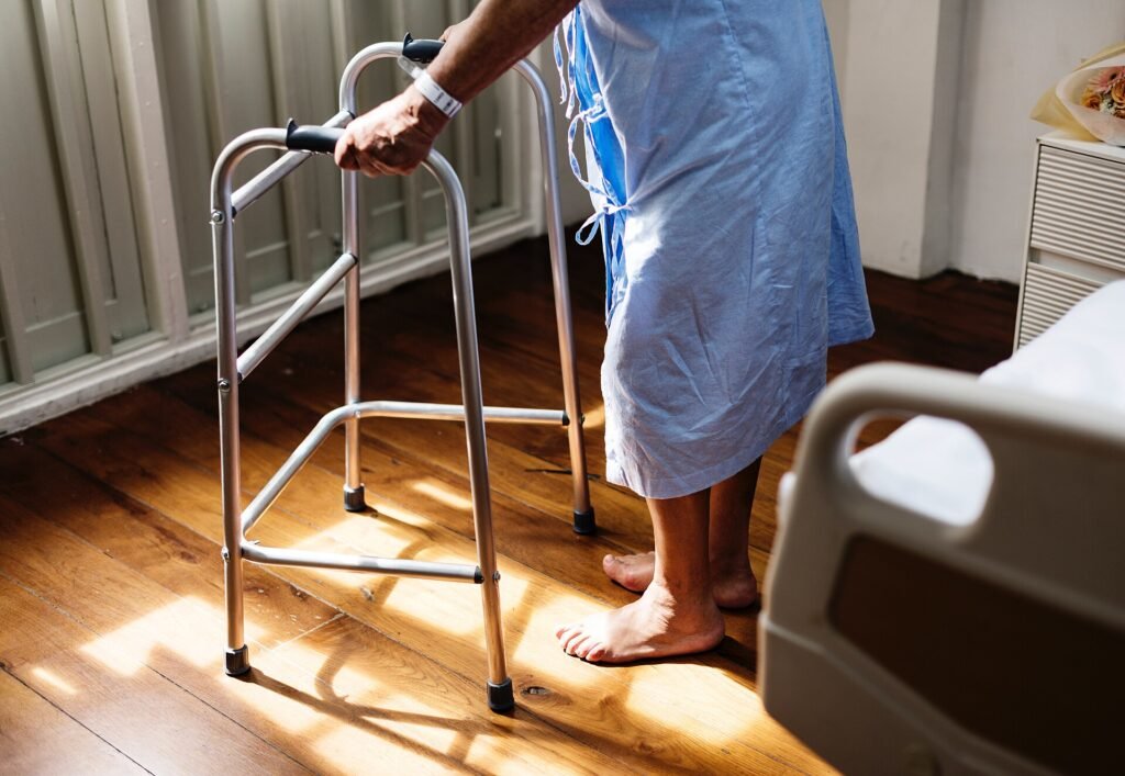 A woman supporting herself with a walking frame, the kind of support used in early recovery after joint replacement