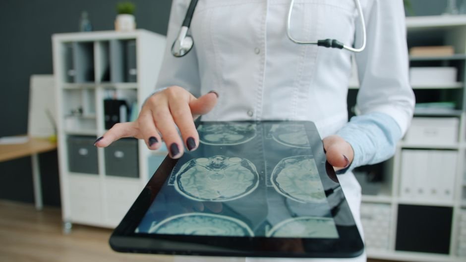 Doctor reviewing scans on a tablet, representing remote coordination of elderly parent care